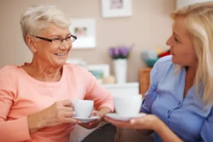 An older woman and her live-in companion chatting over coffee at home in London