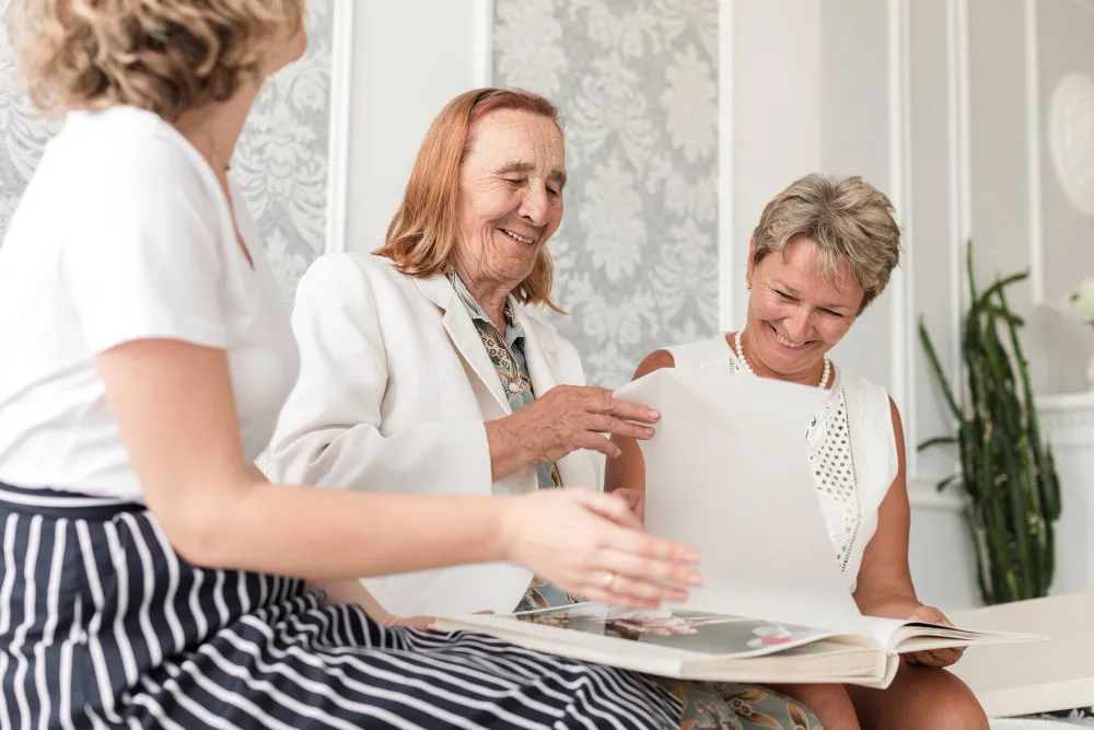 Three generations of a family look through a photo album at home while planning dementia care in London